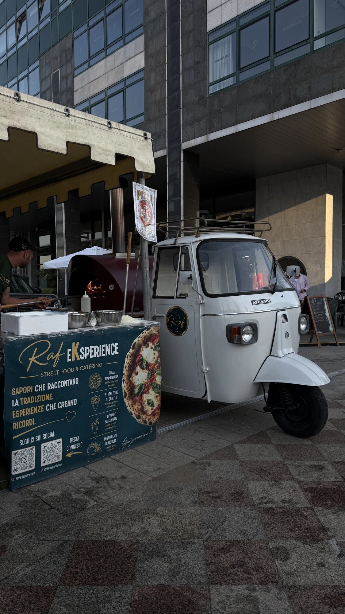 La nostra Apecar bianca con forno a legna acceso durante un evento serale