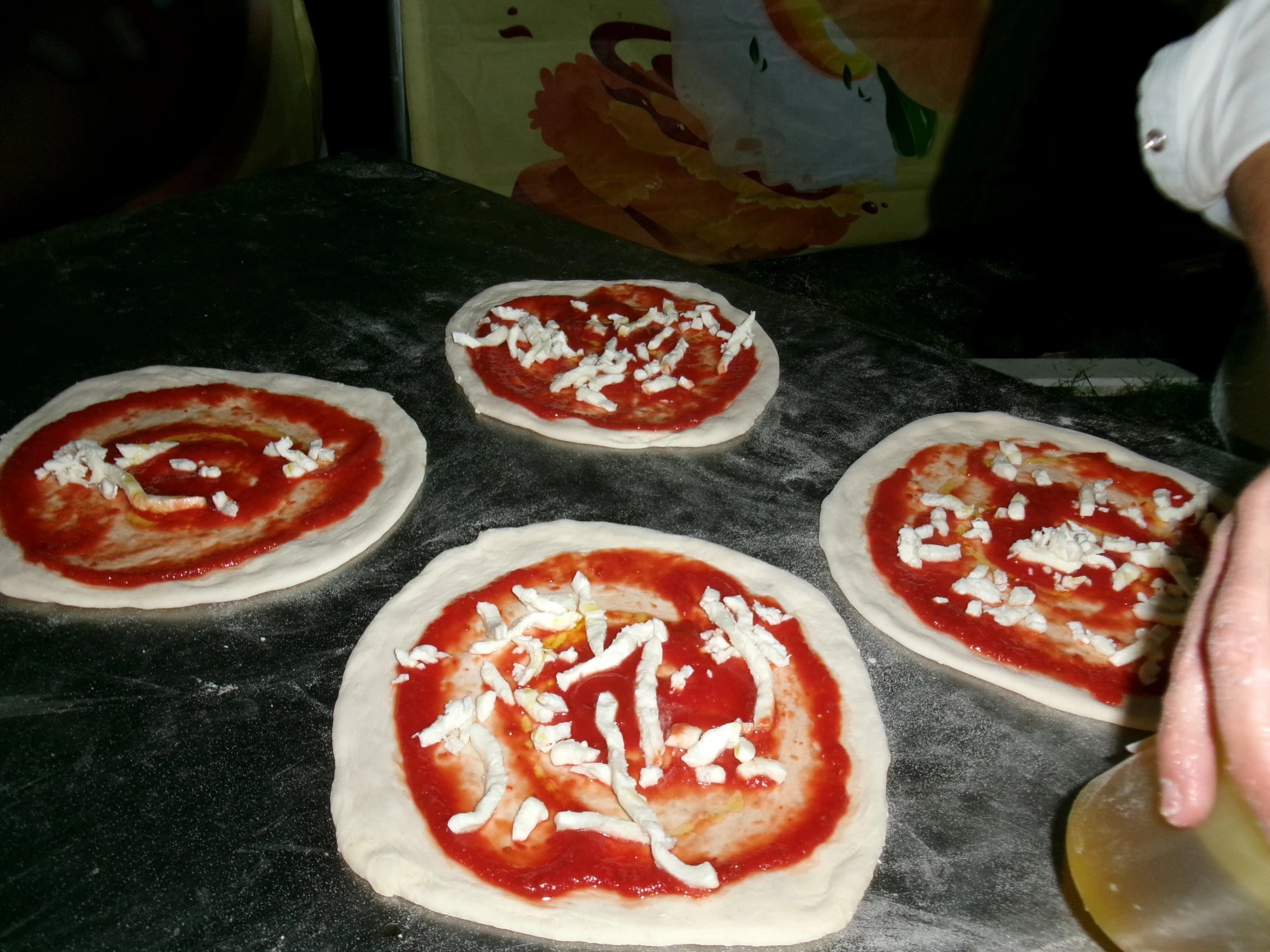 Pizze condite con pomodoro e fiordilatte in preparazione durante la festa